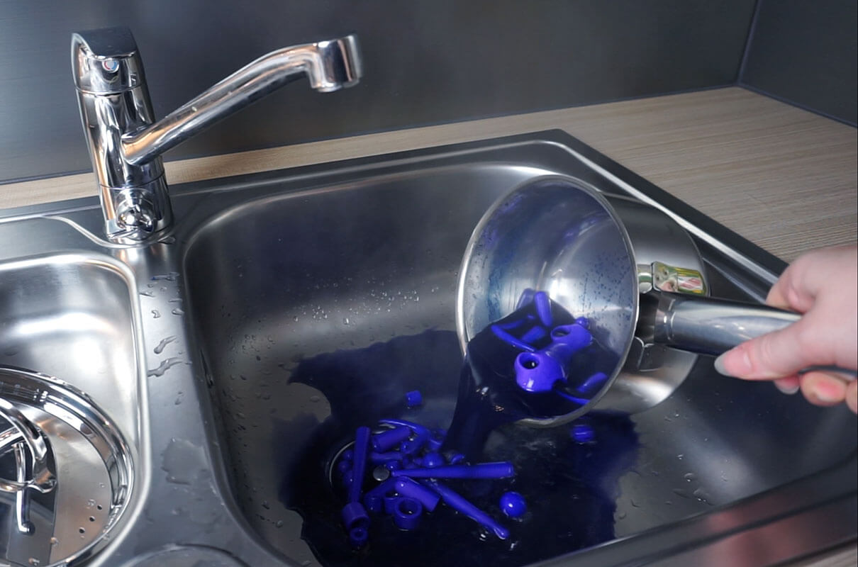 pouring dyed doll pieces and dye in the sink