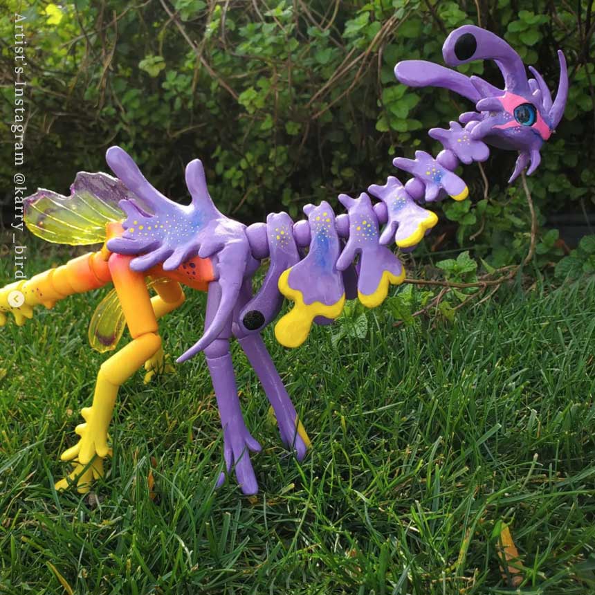 Customized dragon BJD. It's half purple, half yellow/orange with elaborate fins all over its' body.